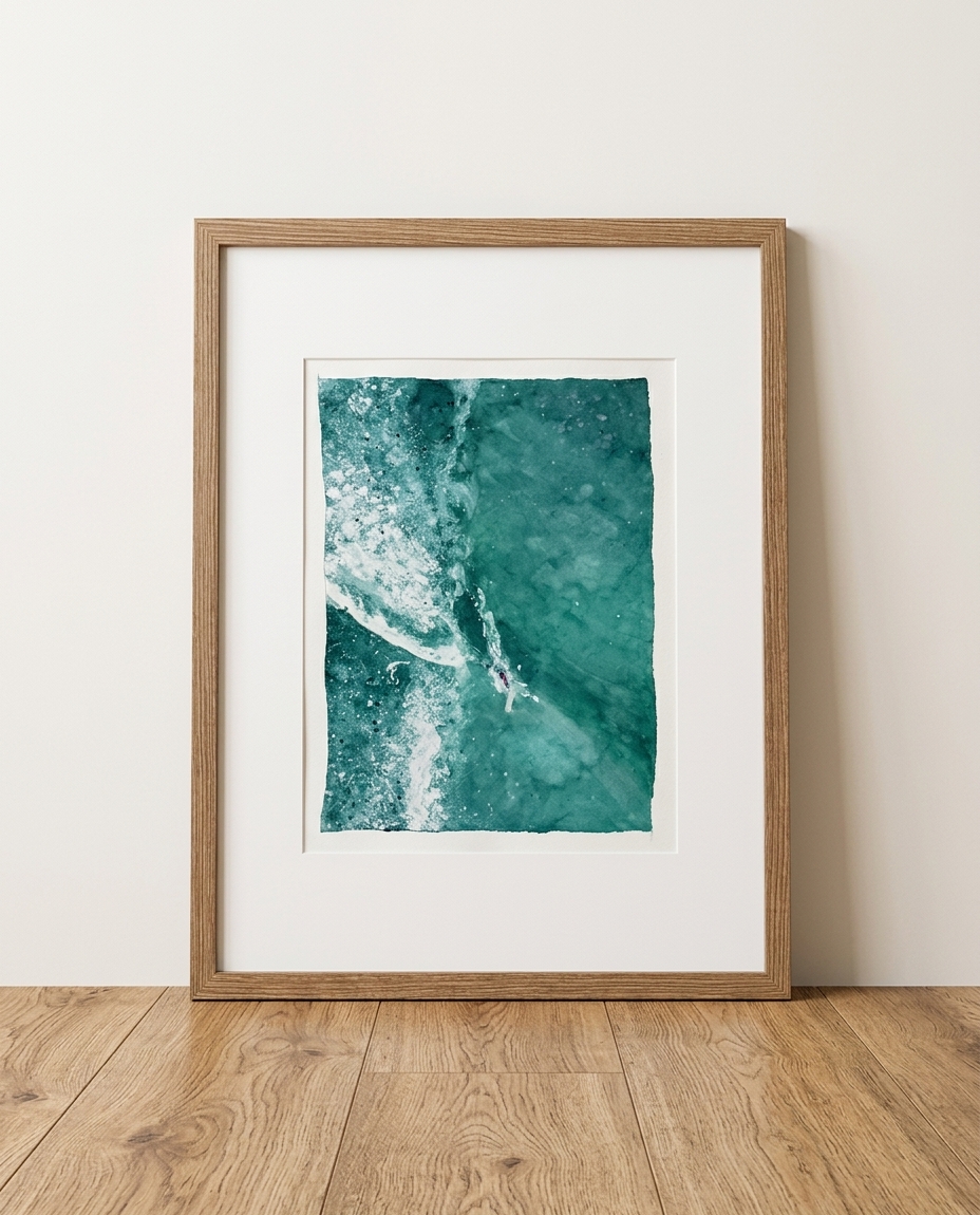 Framed aerial watercolor of a surfer beside a breaking emerald green wave, leaning against a wall