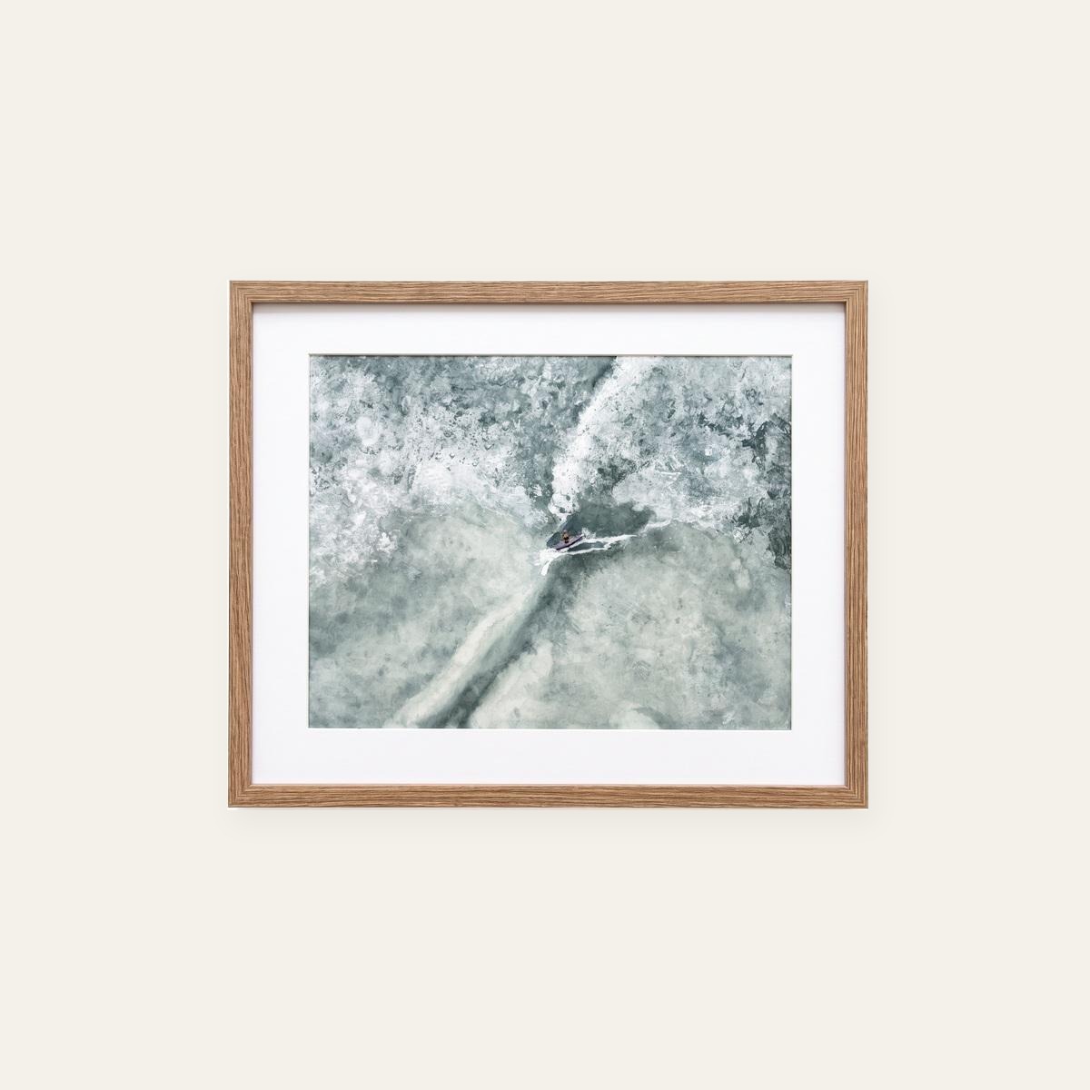 Framed aerial watercolor of a lone surfer carving through misty gray-green whitewater