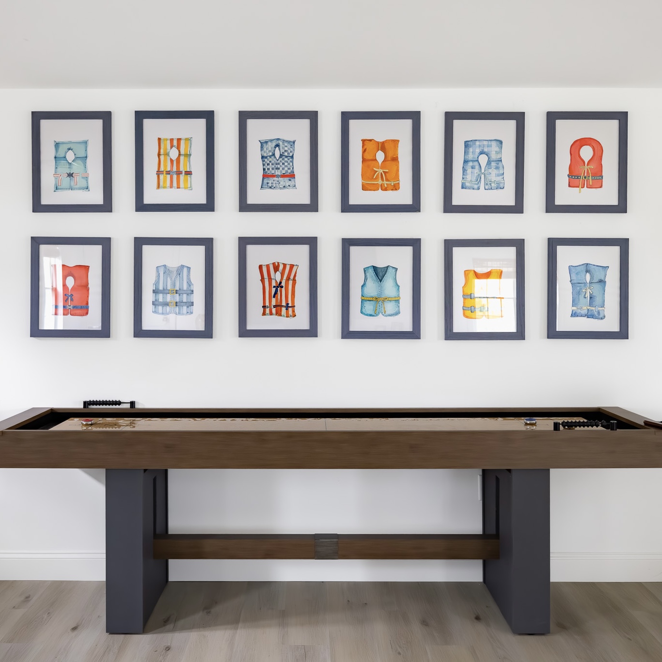 Twelve framed watercolor life vest paintings arranged in a two-row grid on a white wall