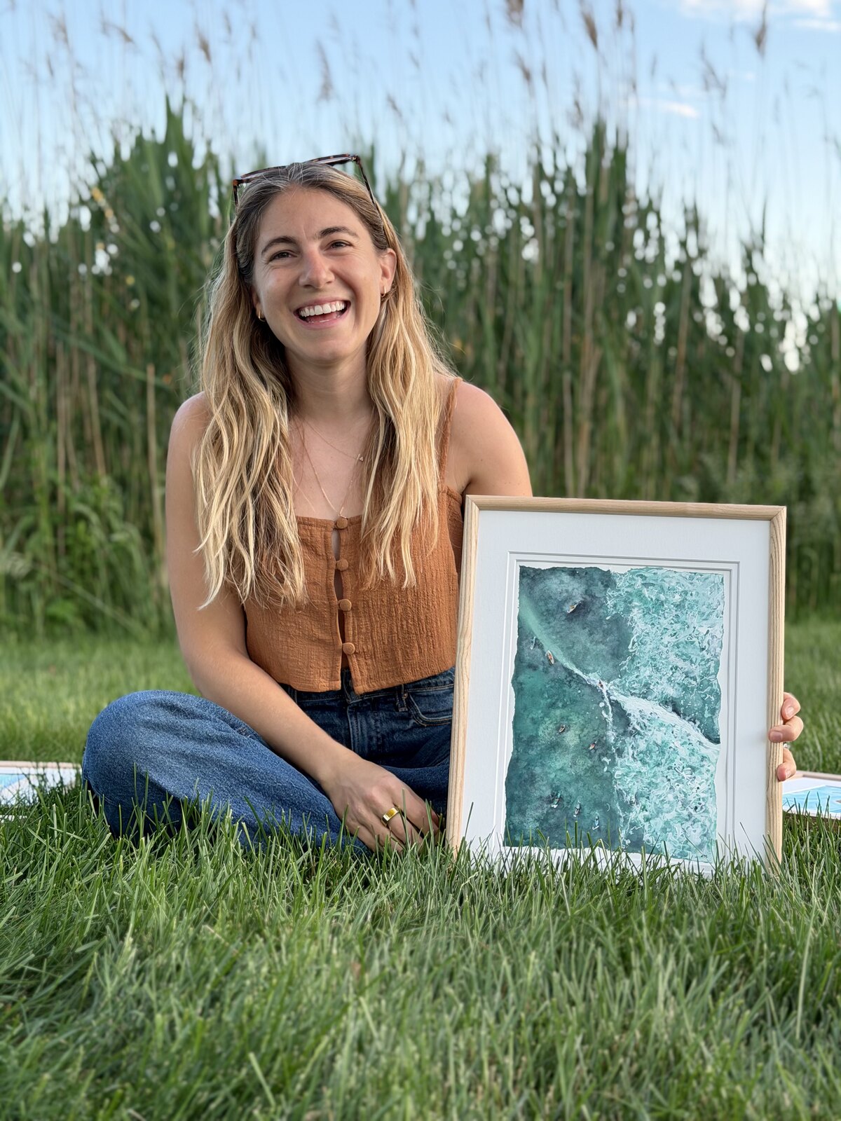 Lynn Moschella holding one of her coastal watercolor paintings